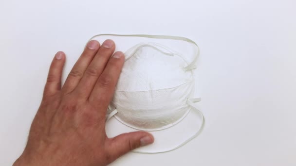 Een mannelijke hand pakt zachtjes een wit medisch masker op van de tafel. — Stockvideo