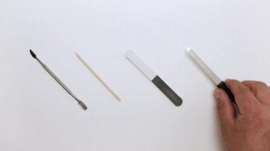 A hand picks up nail files, an orange stick and a trimmer from the table. 