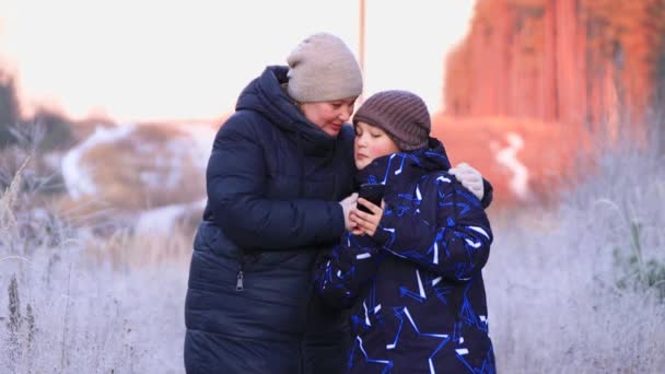 Щаслива мама з сином крупним планом цілується з телефоном в руці . — стокове відео