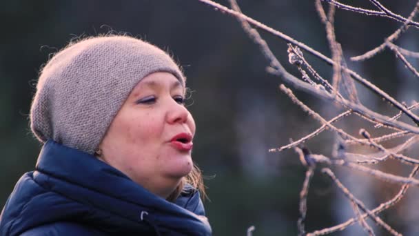 Genç bir kadının yüzü, ağzındaki buharı bir dala üflüyor.. — Stok video