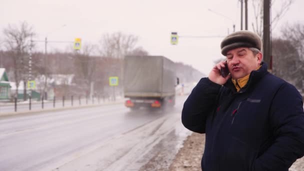 Een serieuze man aan de kant van de weg praat emotioneel aan de telefoon.. — Stockvideo