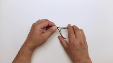 Bir adamın elinin makasla tırnak keserken yakın çekimi..