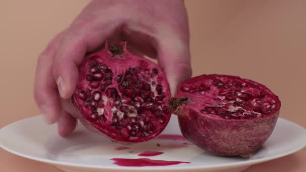 Τα αρσενικά χέρια δείχνουν μισό κόκκινο ρόδι σε λευκό πιάτο.. — Αρχείο Βίντεο