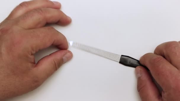Close-up handen inspecteren een metalen nagelvijl. — Stockvideo