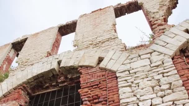 Widok dolny zniszczonej ściany czerwono-białego kamienia z otworami okiennymi. — Wideo stockowe