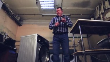 Adam elektrikli tornavidayı alır ve kutunun vidalarını söker..