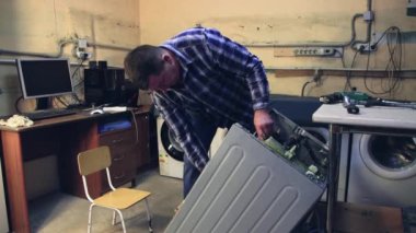 Adam parçaları tek tek çamaşır makinesinin içine sokuyor..