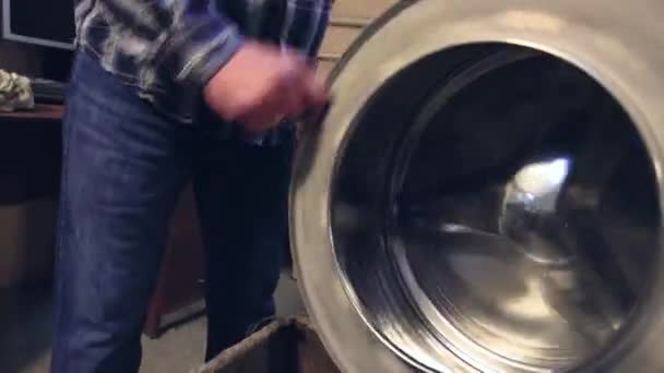 Um homem gira um tambor de metal em uma caixa de plástico com a mão. — Vídeo de Stock