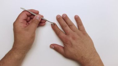 Metal bir kazıyıcının yakın çekimi işaret parmağındaki tırnağı çizer..