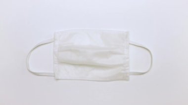 Erkek eller masadan yavaşça beyaz bir tıbbi maske alır.. 