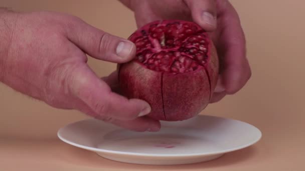 Mužské ruce jemně rozbijí nasekané červené granátové jablko na plátky. — Stock video