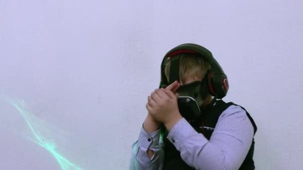 En pojke i augmented reality-hörlurar och hörlurar skjuter en pistol. — Stockvideo