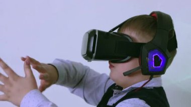 Sanal gerçeklik kulaklığı ve kulaklığı olan bir çocuk uzayda elleriyle oynuyor.