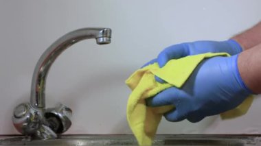 Mavi eldivenli erkek eller dikkatlice kırmızı narı sarı havluyla kurutur.