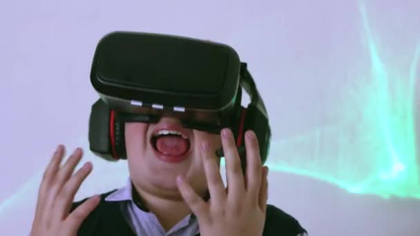 Ein Junge mit Virtual-Reality-Headset und Kopfhörern schreit und fasst sich an den Kopf. — Stockvideo