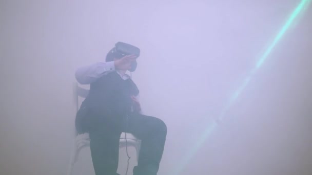 Un ragazzo con un auricolare realtà virtuale balla allegramente nel fumo. — Video Stock