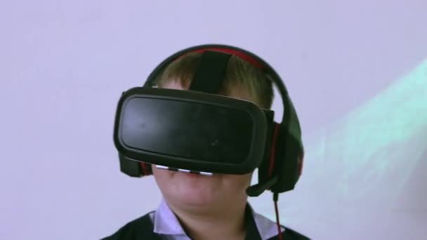 Um menino em um fone de ouvido realidade virtual e fones de ouvido dança lentamente. — Vídeo de Stock