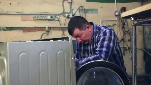 El hombre toma un destornillador eléctrico, desenrosca la pieza y sonríe. — Vídeos de Stock