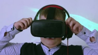 Sanal gerçeklik kulaklığı ve kulaklığı olan bir çocuk kaskı ayarlar..