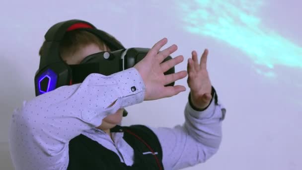 A boy in a virtual reality headset and headphones plays in profile. — Stock Video