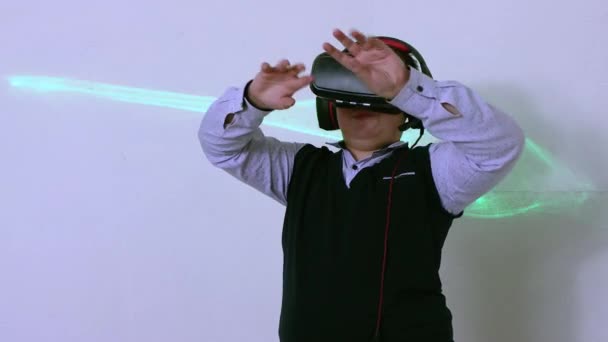 Een jongen in een virtual reality headset en een koptelefoon beweegt zijn handen in de ruimte. — Stockvideo