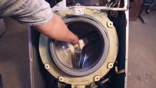 Eine Männerhand dreht die Trommel einer Waschmaschine zu einer Waschmaschine. — Stockvideo