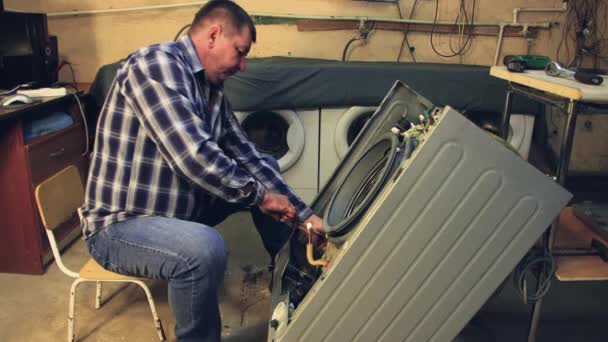Чоловік затягує болти барабану пральної машини за допомогою гніздового ключа . — стокове відео