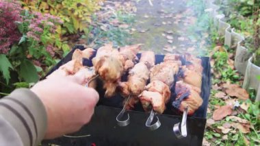 Yakından bir adam kömür ızgarasının üzerindeki et şişini çeviriyor.. 