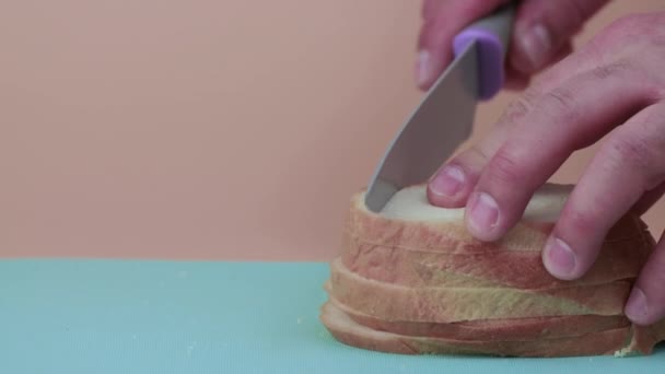 Gros plan Les mains masculines coupent plusieurs morceaux de pain blanc en tranches. — Video