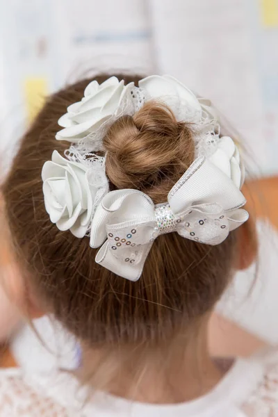 Close-up of a girls hairstyle with a bun of hair tied with a white bow. Royalty Free Stock Images