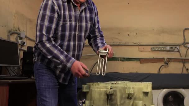 Ein Mann steckt ein Heizelement in die Trommel der Waschmaschine. — Stockvideo