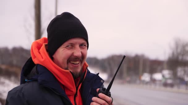 Un homme d'affaires avec une moustache sourit et parle sur un talkie-walkie. — Video