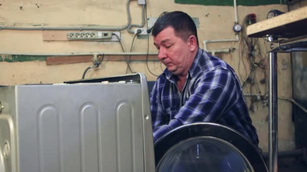 A male specialist disassembles a washing machine — Stock Video