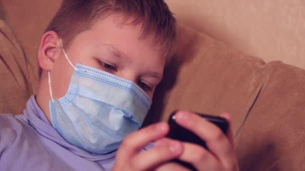 Happy boy in een masker op een smartphone speelt mobiele games. — Stockvideo