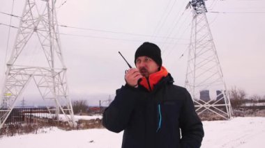 İş adamı, gri gökyüzüne karşı telsizle konuşuyor.