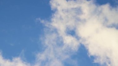 Gökyüzü mavi ve beyaz kümülüs bulutları hızla süzülüyor..