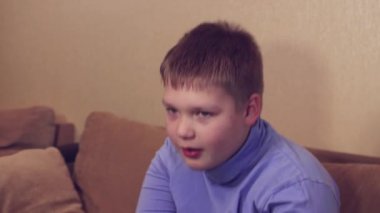 Mutlu çocuk kanepede oturuyor ve dans ediyor. Sağlıklı dinlenme.