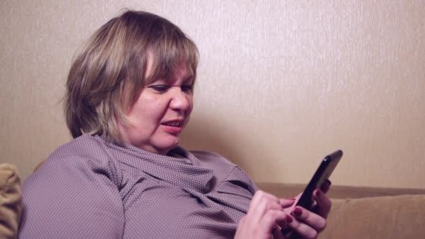 En voksen kvindelig kunde, der holder en smartphone i hånden, foretager køb. – Stock-video