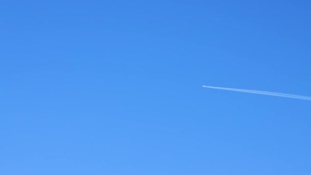 Jet uçağı mavi gökyüzünün arka planına doğru hızla uçar.. — Stok video