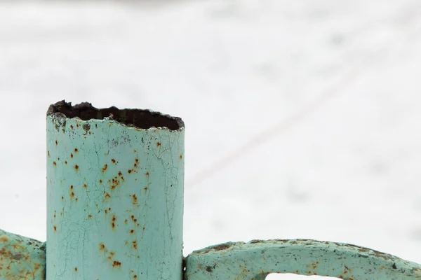 Una tubería de metal oxidado sobresale sobre una cerca de hierro. — Foto de Stock