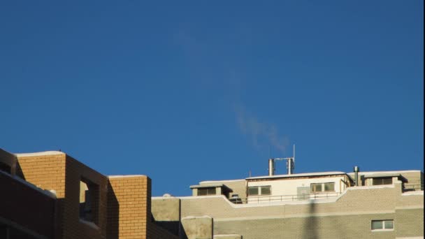 Céu azul e fumaça saindo da chaminé no telhado da casa. — Vídeo de Stock