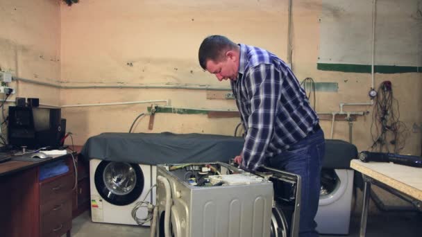 Ένας άνδρας ειδικός επιθεωρεί τις λεπτομέρειες ενός πλυντηρίου ρούχων. — Αρχείο Βίντεο
