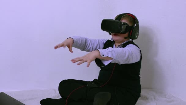 Een jongen met een bril en een augmented reality headset verzamelt virtuele objecten — Stockvideo