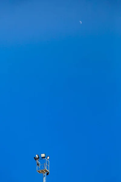 Bir kayak merkezinde spot ışıkları ve gökyüzünde ay ışığı olan bir sütun.. 