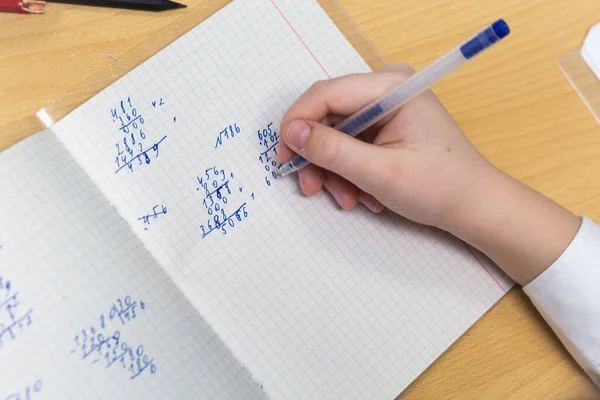 The girls hand with a fountain pen with blue ink solves examples in mathematics — Stock Photo, Image