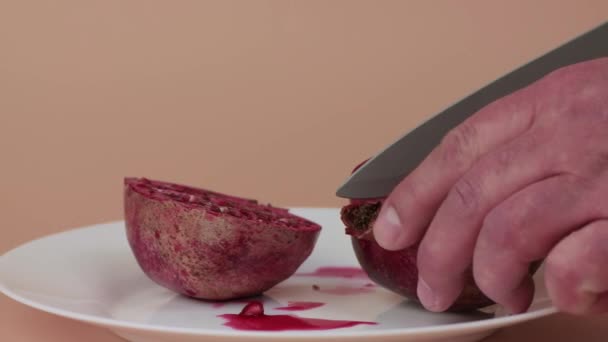 Mãos masculinas close-up com uma faca de cozinha cortar uma romã em fatias — Vídeo de Stock