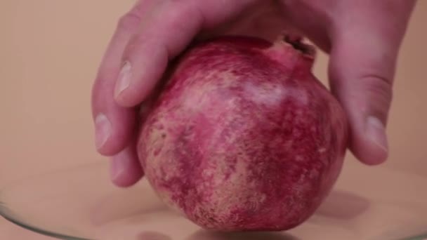 Las manos masculinas de primer plano ponen y rotan una granada roja en un plato transparente. — Vídeos de Stock