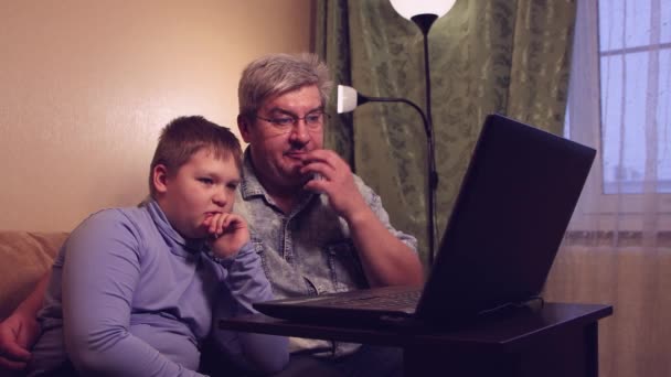 Το αγόρι και ο μπαμπάς του μελετούν στο διαδίκτυο στο σπίτι παρακολουθώντας και ακούγοντας το μάθημα. — Αρχείο Βίντεο