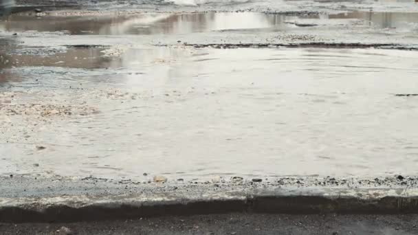 近くの車の穴や泥の水たまりと道路に沿って駆動します. — ストック動画