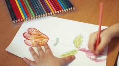 Çocukların elleri bir vazoya yakın plan kalemle sembolik bir çiçek çizer..